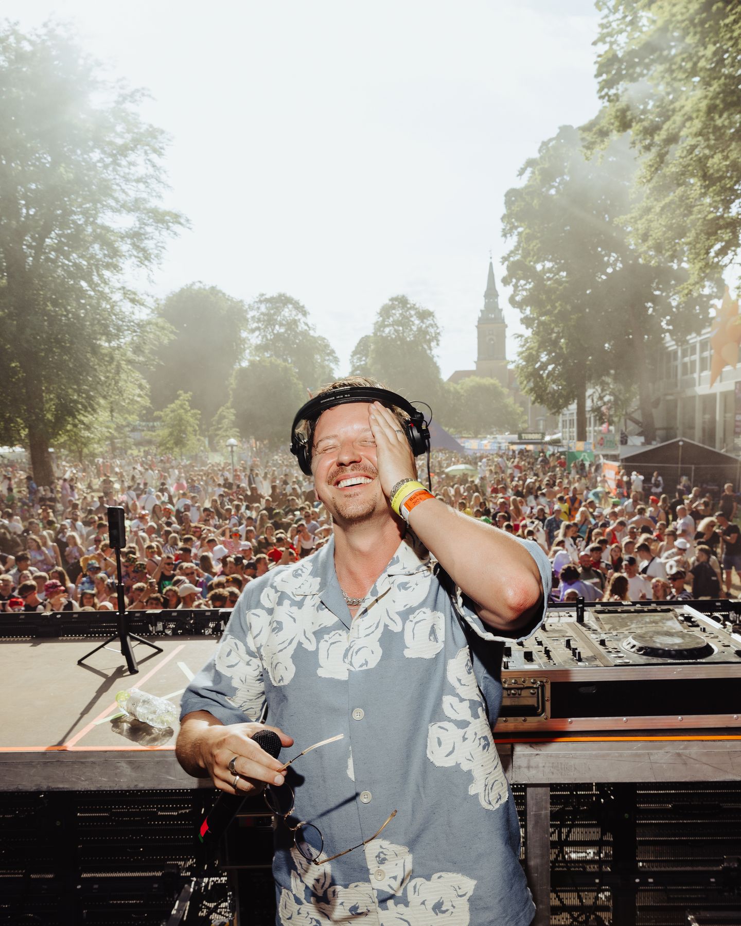 Frederik Thode smiler bag DJ-pulten foran et stort publikum
